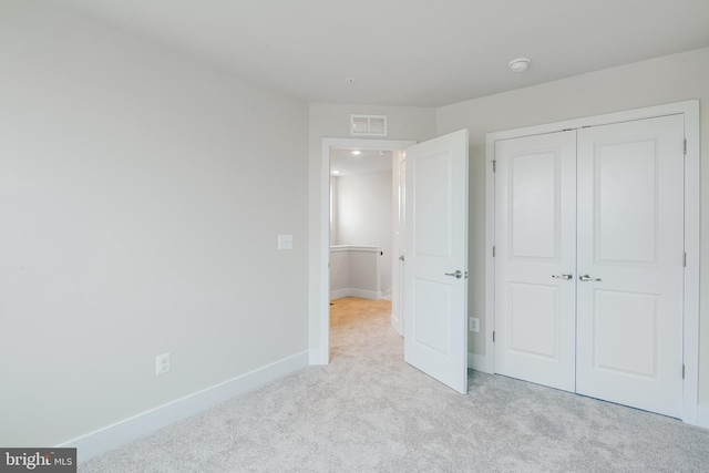 unfurnished bedroom with light colored carpet and a closet