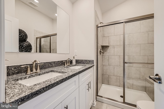 bathroom with tile patterned flooring, an enclosed shower, vanity, and toilet