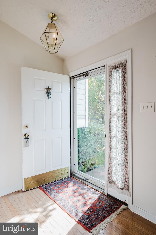 foyer entrance featuring hardwood / wood-style floors, a chandelier, and a textured ceiling