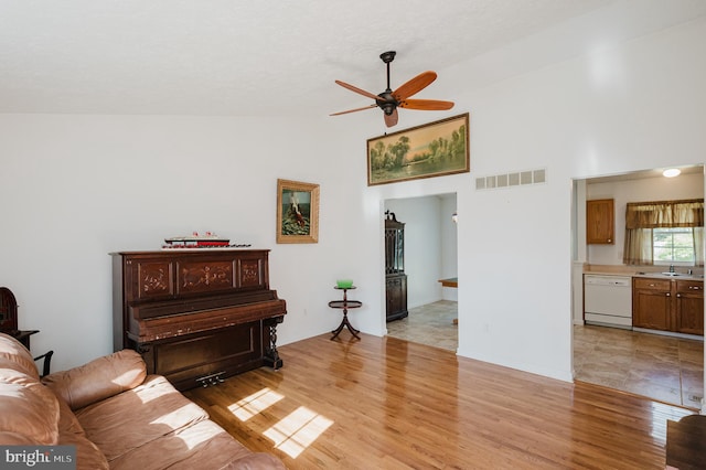 living room featuring ceiling fan, light wood-type flooring, sink, and high vaulted ceiling