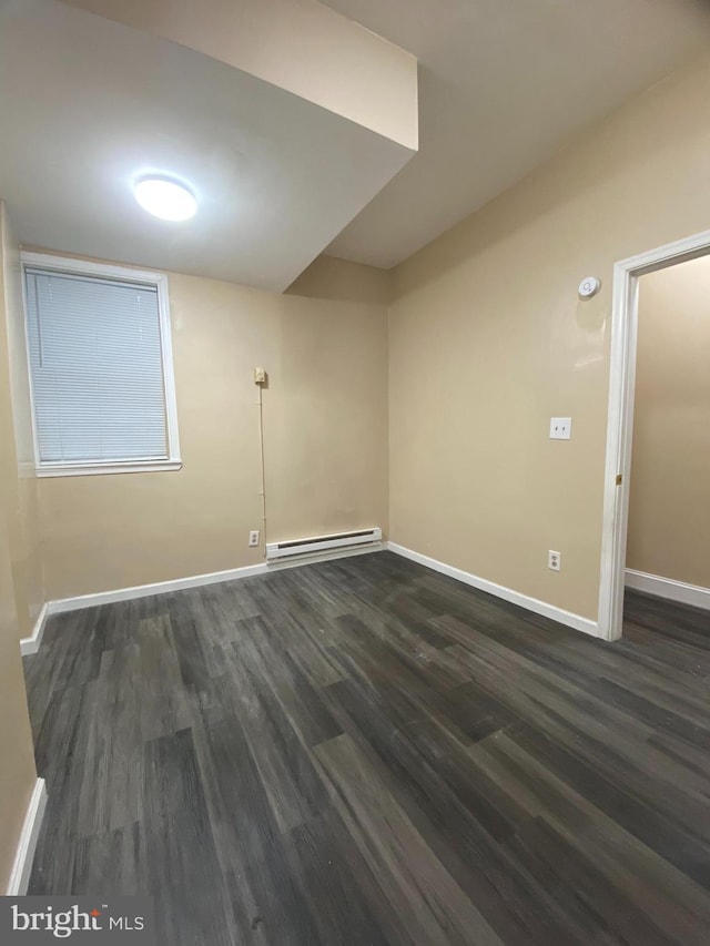 empty room with baseboard heating and dark wood-type flooring