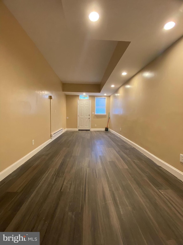 additional living space with dark wood-type flooring and a baseboard radiator