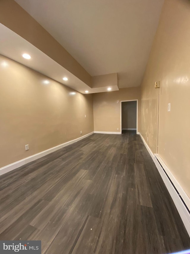 unfurnished room with dark wood-type flooring and a baseboard radiator