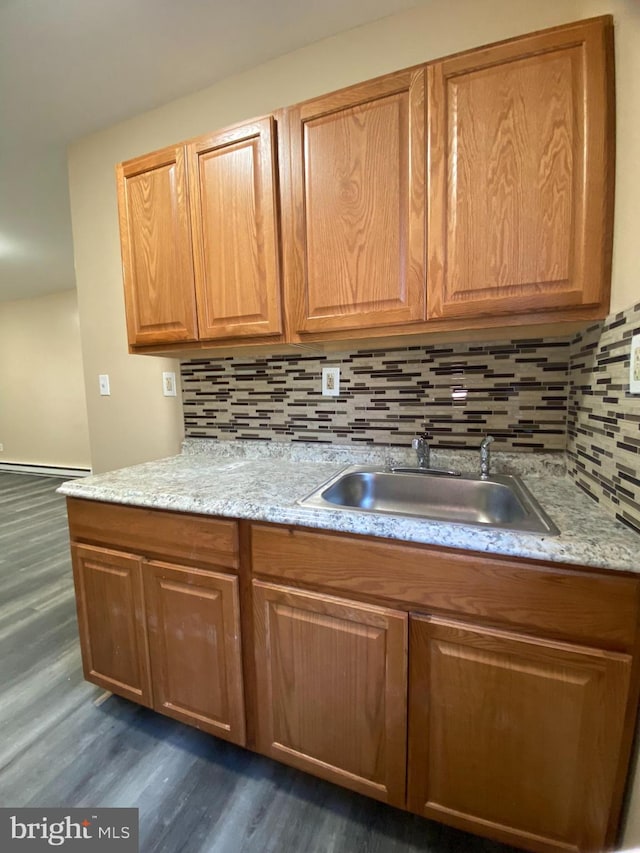 kitchen with decorative backsplash, light stone counters, dark wood-type flooring, and sink