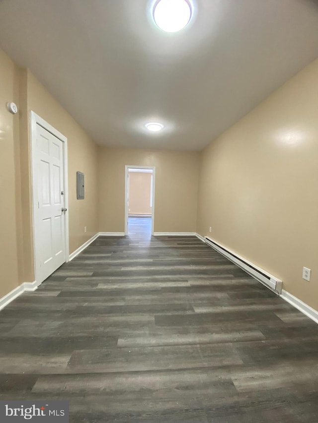 spare room with a baseboard heating unit, electric panel, and dark hardwood / wood-style floors