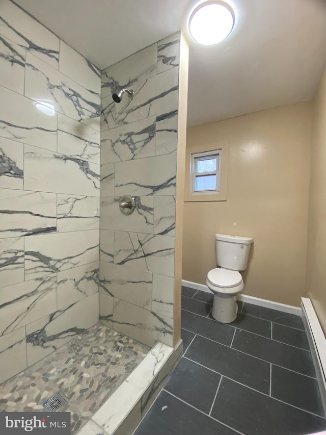 bathroom featuring a tile shower, a baseboard heating unit, tile patterned flooring, and toilet