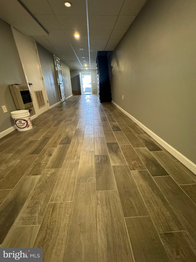 hallway with a paneled ceiling and hardwood / wood-style flooring