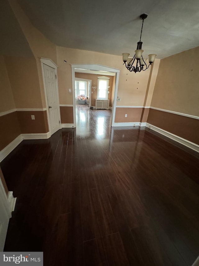 unfurnished dining area with dark hardwood / wood-style floors and a chandelier