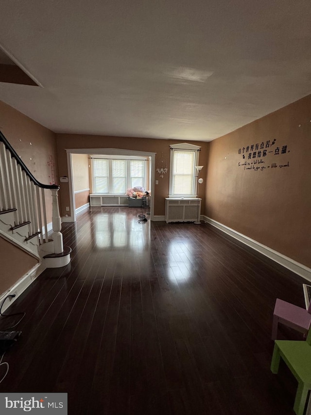 unfurnished living room featuring radiator heating unit and dark wood-type flooring