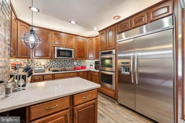 kitchen with backsplash, light stone countertops, stainless steel appliances, light hardwood / wood-style flooring, and decorative light fixtures