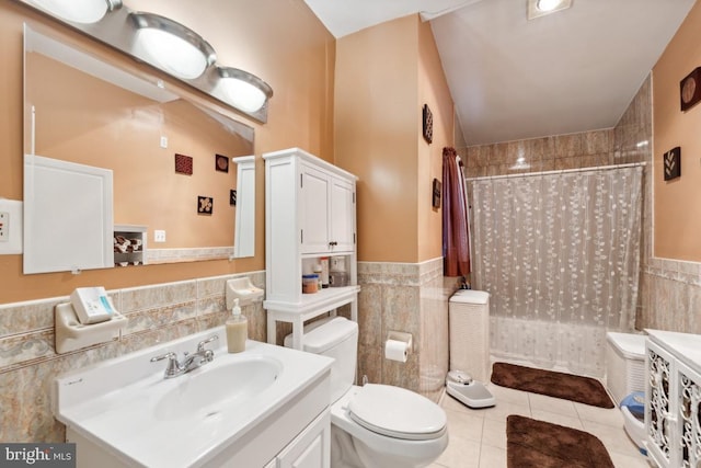 bathroom featuring vanity, toilet, tile patterned flooring, tile walls, and vaulted ceiling