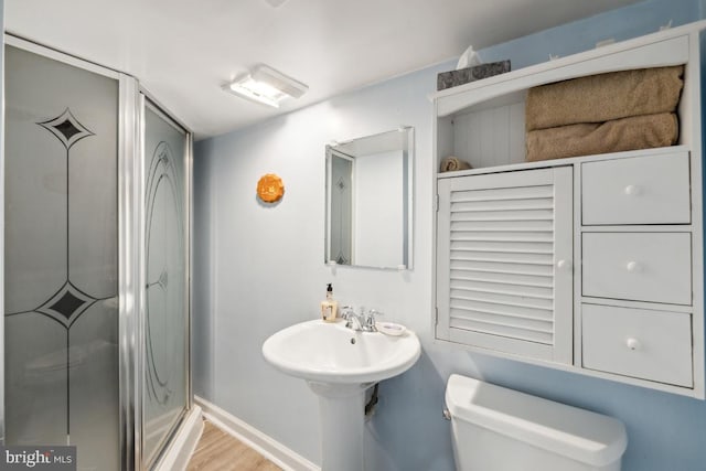 bathroom with hardwood / wood-style floors, a shower with shower door, and toilet