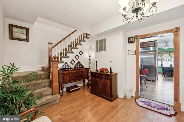 interior space featuring ceiling fan with notable chandelier and light hardwood / wood-style floors