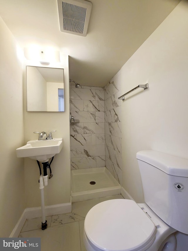 bathroom featuring tiled shower and toilet