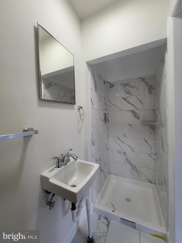 full bathroom featuring a stall shower, marble finish floor, and a sink