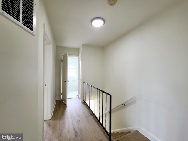 hall featuring baseboards, an upstairs landing, visible vents, and light wood-type flooring