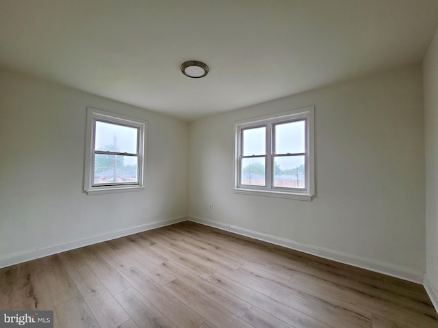 empty room with plenty of natural light, baseboards, and wood finished floors