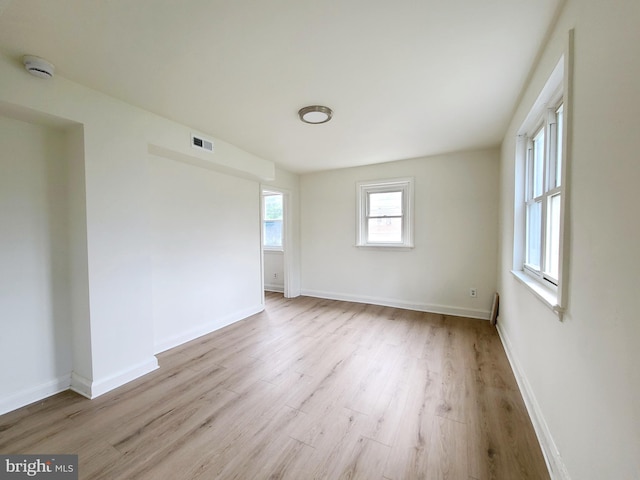empty room with baseboards, visible vents, and wood finished floors