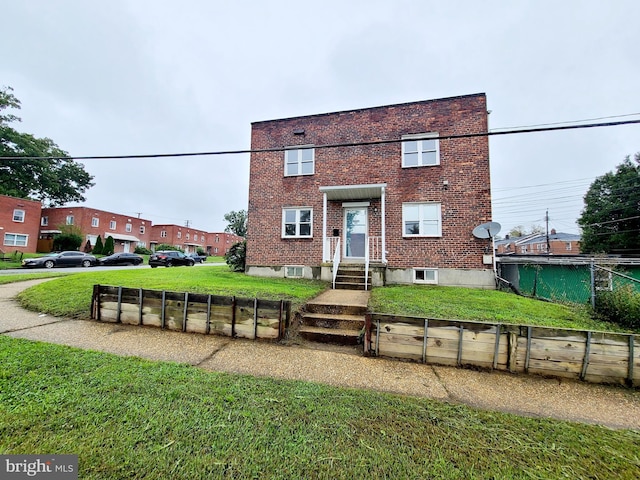 view of front of property featuring brick siding, fence, and a front lawn