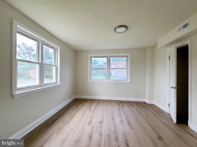 unfurnished room featuring baseboards, visible vents, and light wood-style floors