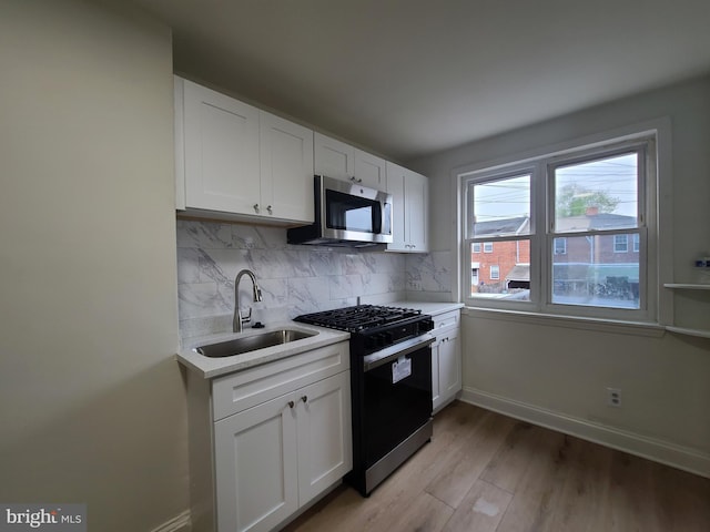 kitchen featuring light countertops, stainless steel microwave, decorative backsplash, range with gas cooktop, and a sink