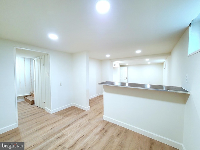 kitchen with baseboards, light wood-style floors, stainless steel counters, and recessed lighting