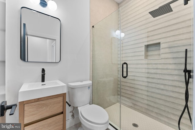 bathroom featuring vanity, a shower with shower door, and toilet