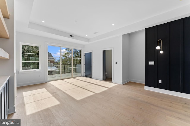 unfurnished living room with light hardwood / wood-style floors and a raised ceiling