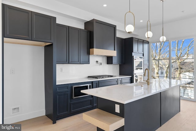 kitchen with a kitchen island with sink, hanging light fixtures, a healthy amount of sunlight, and sink