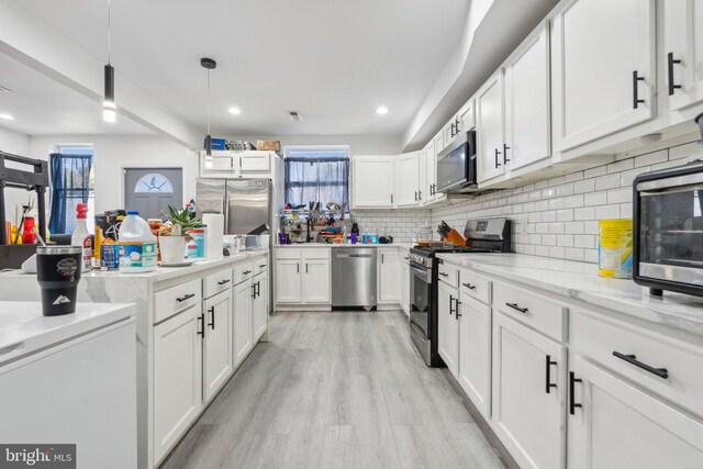 kitchen with light hardwood / wood-style floors, decorative light fixtures, backsplash, white cabinets, and appliances with stainless steel finishes