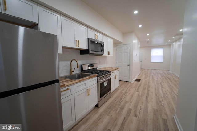 kitchen featuring butcher block countertops, sink, stainless steel appliances, and white cabinets