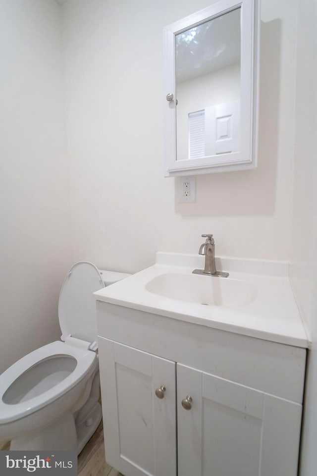 bathroom featuring wood-type flooring, vanity, and toilet