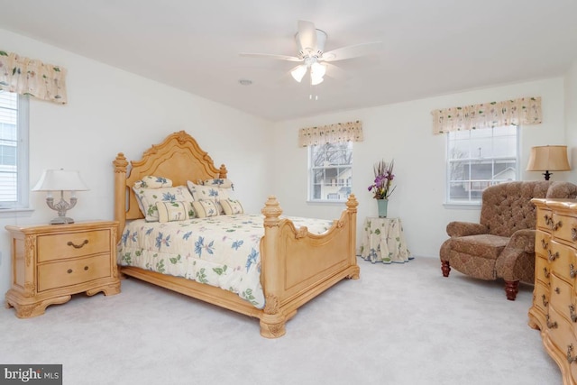 bedroom with ceiling fan, light colored carpet, and multiple windows