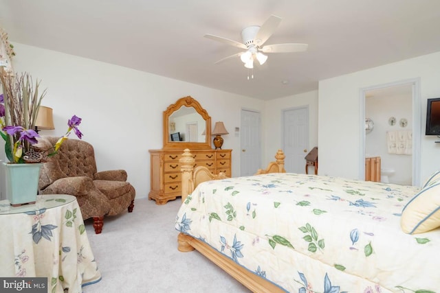 carpeted bedroom with ensuite bath and ceiling fan