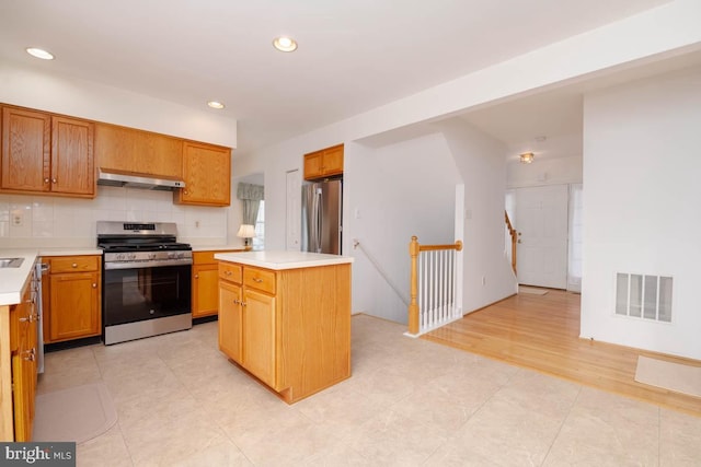 kitchen featuring tasteful backsplash, light tile patterned floors, a kitchen island, and appliances with stainless steel finishes