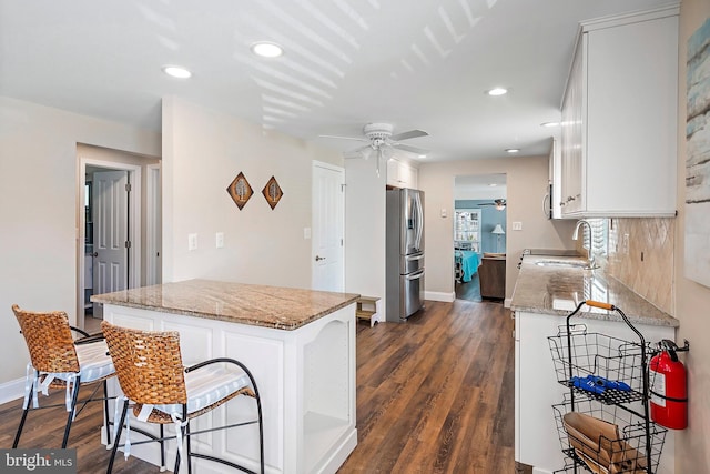 kitchen with stainless steel refrigerator with ice dispenser, dark wood-type flooring, ceiling fan, and white cabinets