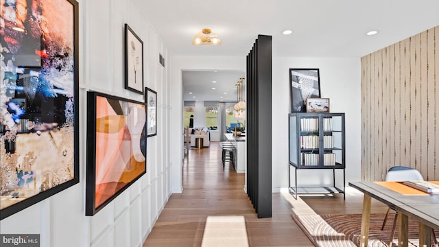 hallway with light wood-type flooring and wooden walls