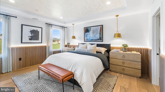 bedroom featuring light hardwood / wood-style flooring and a tray ceiling