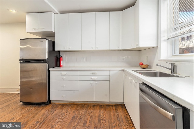 kitchen with sink, dark hardwood / wood-style flooring, stainless steel appliances, decorative backsplash, and white cabinets