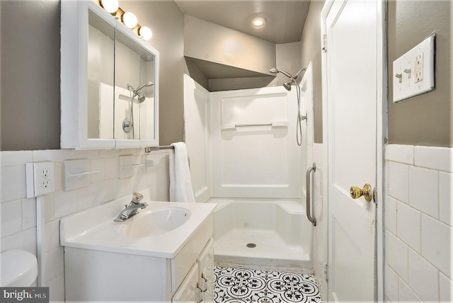 bathroom featuring a shower, tile walls, vanity, and toilet