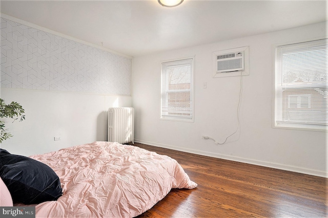 bedroom with an AC wall unit, radiator heating unit, and dark hardwood / wood-style flooring