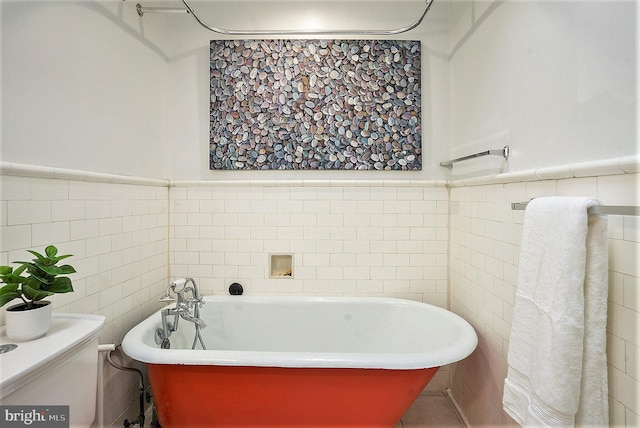 bathroom featuring a washtub, tile walls, and toilet