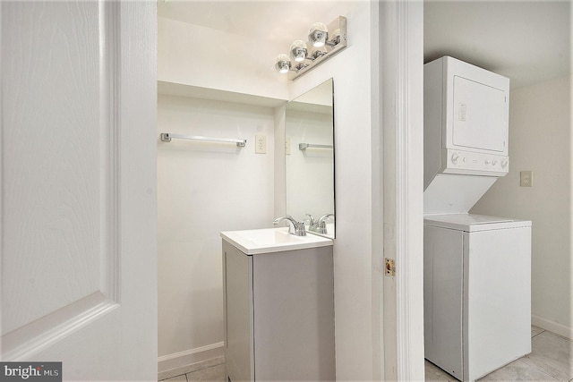 laundry area with stacked washer / dryer, sink, and light tile patterned floors