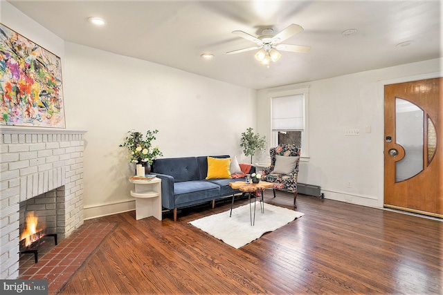 living room with ceiling fan, dark hardwood / wood-style flooring, and a brick fireplace