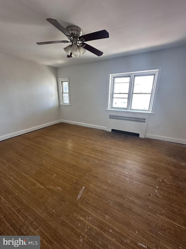 spare room featuring radiator, dark hardwood / wood-style flooring, and ceiling fan