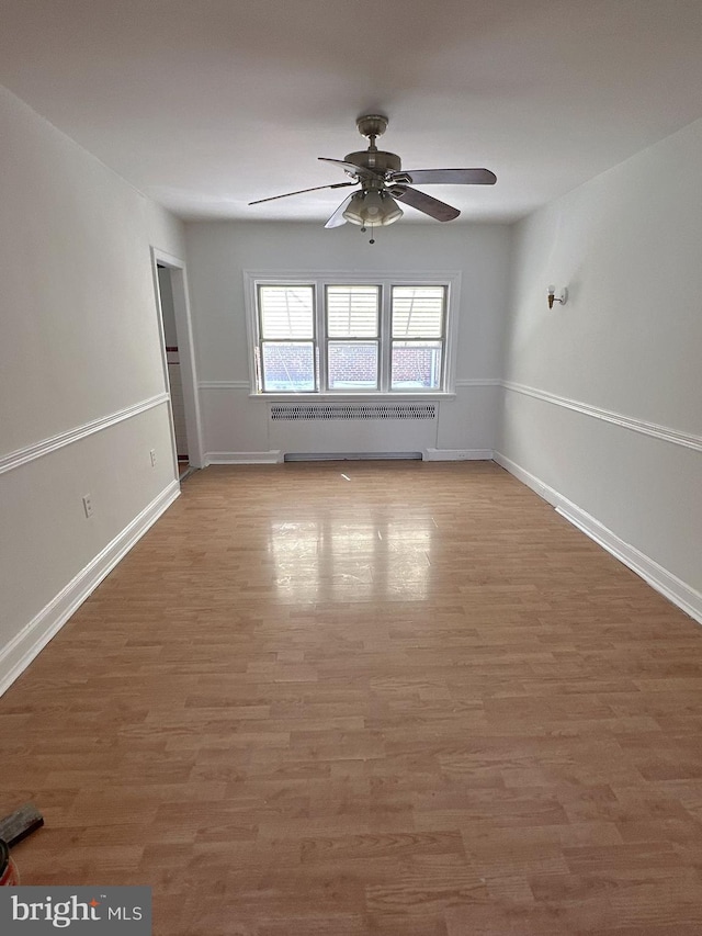 unfurnished room with ceiling fan, hardwood / wood-style floors, and radiator heating unit