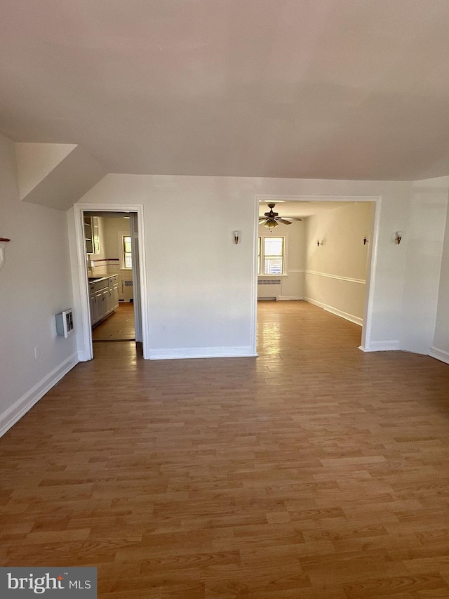 unfurnished living room with heating unit, wood-type flooring, vaulted ceiling, and ceiling fan