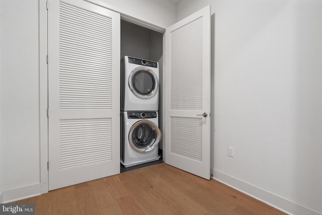 clothes washing area featuring stacked washer / dryer and wood-type flooring