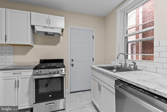 kitchen featuring sink, white cabinetry, appliances with stainless steel finishes, light stone countertops, and decorative backsplash