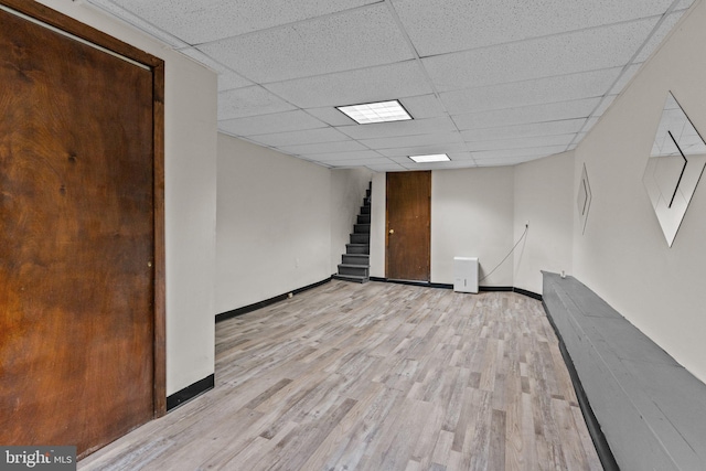 basement with a paneled ceiling and light hardwood / wood-style flooring